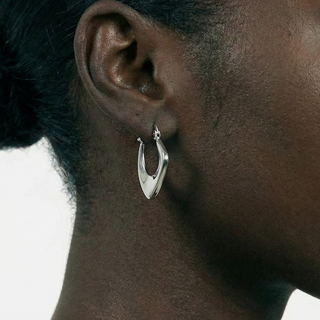 Close-up of an ear wearing a silver hoop earring with a blurred background
