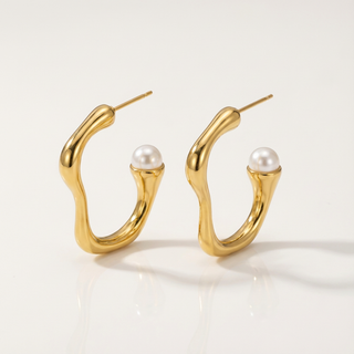 Gold hoop earrings with pearl centers on a light background