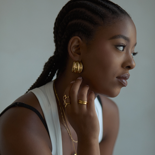 Mira Ribbed Dome Hoop Earrings in gold, worn with layered rings and necklaces